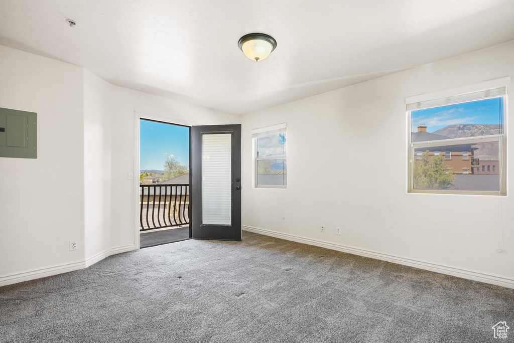 Carpeted spare room featuring baseboards and electric panel