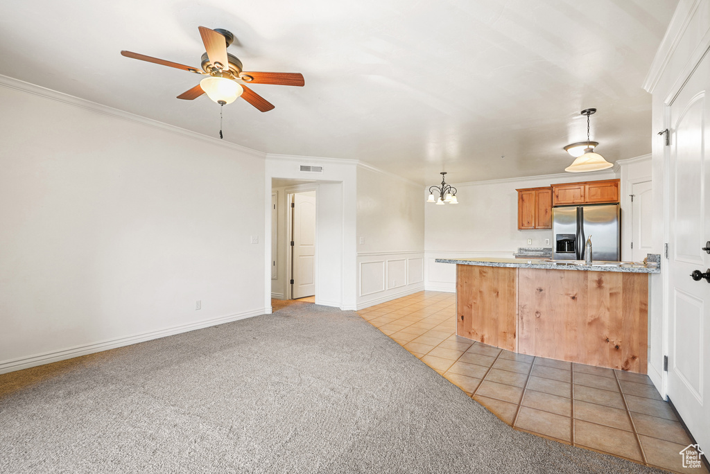 Kitchen with crown molding, light colored carpet, a peninsula, stainless steel refrigerator with ice dispenser, and visible vents