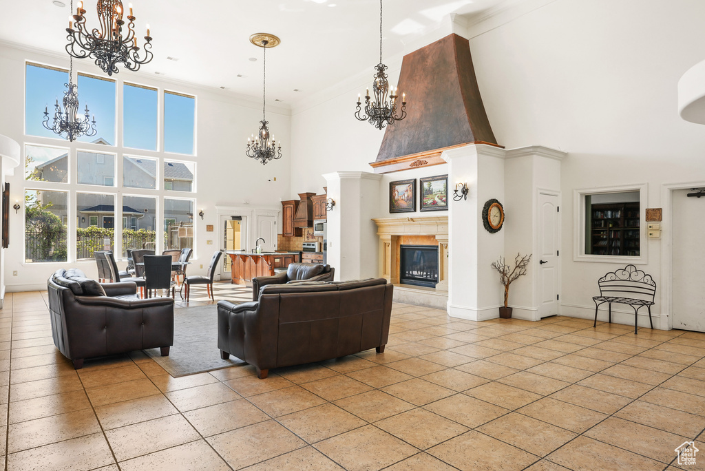 Living area featuring a high ceiling, an inviting chandelier, a glass covered fireplace, and light tile patterned floors
