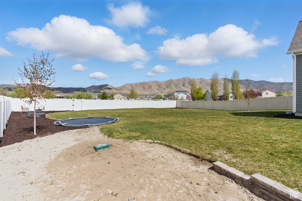 View of yard featuring a mountain view, a fenced backyard, and a trampoline