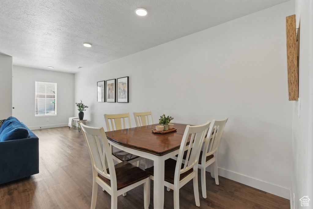 Dining space featuring a textured ceiling, baseboards, recessed lighting, and wood finished floors