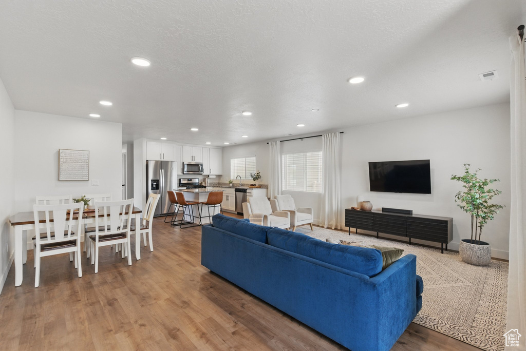 Living room featuring recessed lighting, baseboards, visible vents, and light wood-type flooring