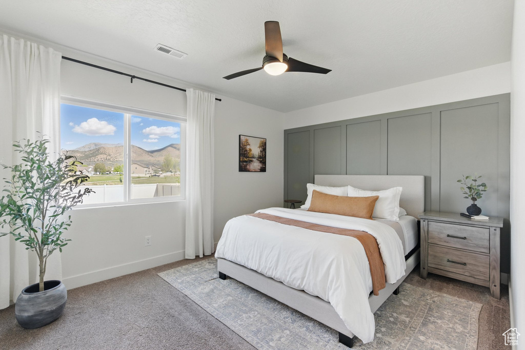 Carpeted bedroom featuring baseboards, visible vents, a mountain view, and ceiling fan