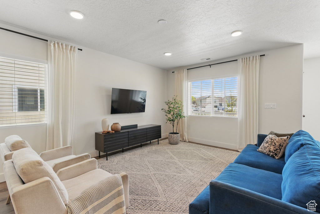 Living room featuring recessed lighting, a textured ceiling, and baseboards