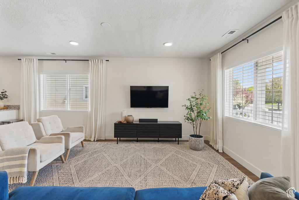 Living area featuring recessed lighting, a textured ceiling, visible vents, and baseboards