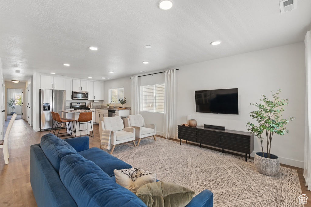 Living area with recessed lighting, baseboards, visible vents, and light wood-style flooring
