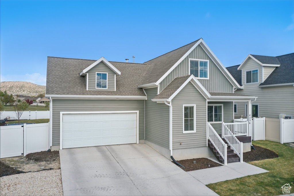Craftsman-style house featuring a shingled roof, board and batten siding, fence, and driveway