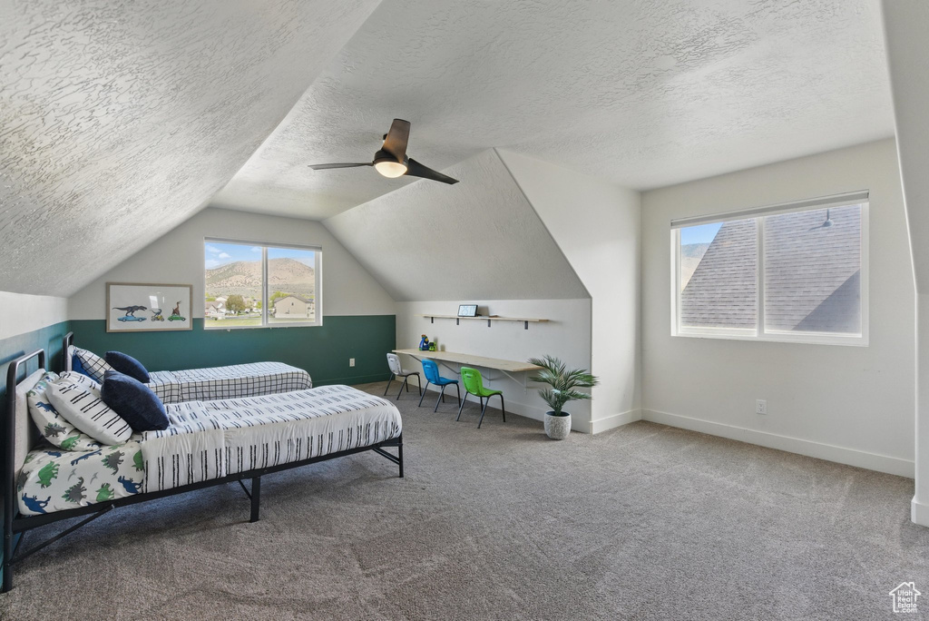 Carpeted bedroom featuring a ceiling fan, a textured ceiling, vaulted ceiling, and baseboards