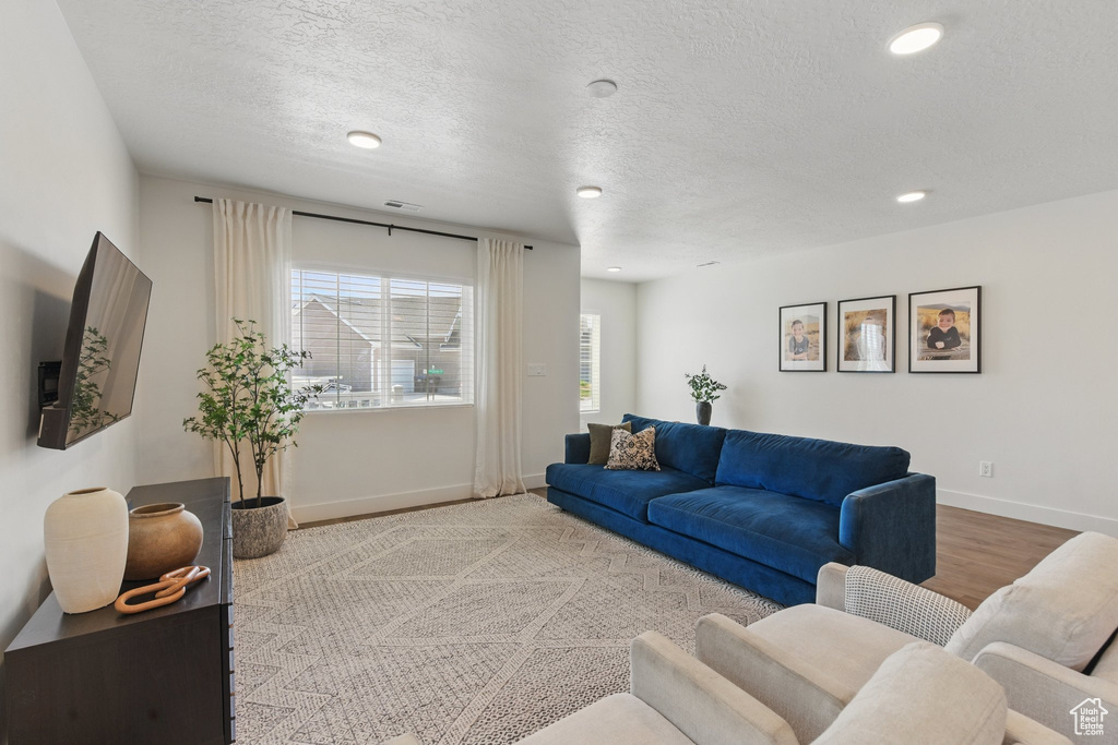 Living area with visible vents, wood finished floors, baseboards, recessed lighting, and a textured ceiling