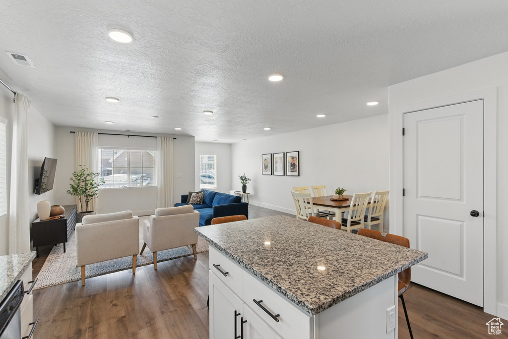 Kitchen featuring a kitchen island, a kitchen bar, visible vents, dark wood finished floors, and white cabinetry