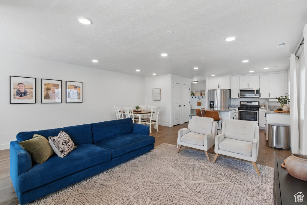 Living area with recessed lighting, light wood finished floors, and visible vents