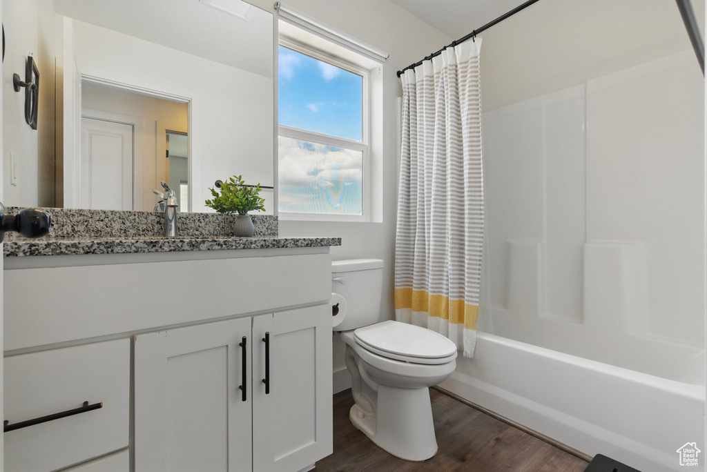 Full bathroom featuring vanity, shower / bath combo, toilet, and wood finished floors