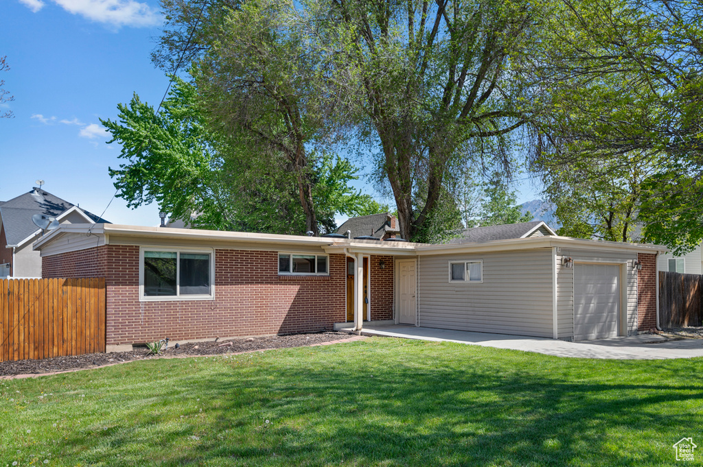 Ranch-style house with a garage, fence, a front lawn, and brick siding