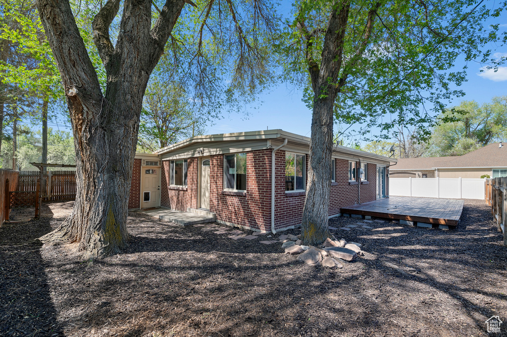 Exterior space with brick siding, a fenced backyard, and a wooden deck