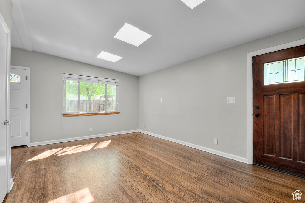 Entryway featuring baseboards, wood finished floors, and vaulted ceiling with skylight