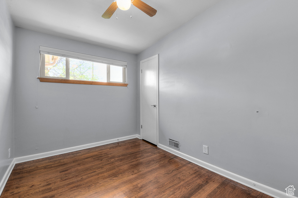 Spare room featuring baseboards, a ceiling fan, dark wood-style flooring, and visible vents