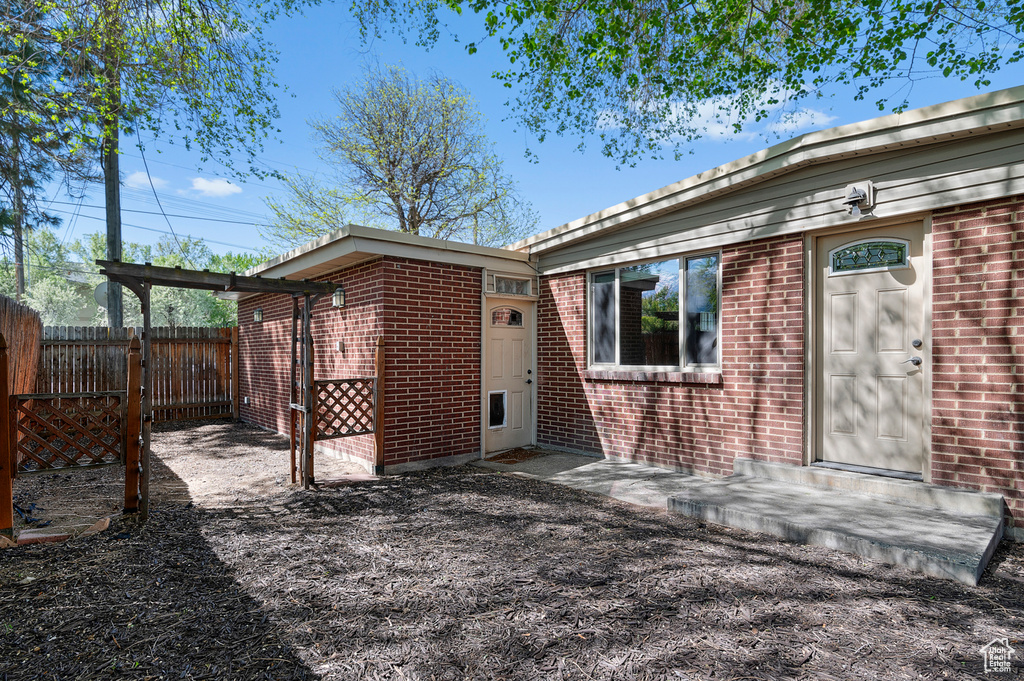 Back of house featuring brick siding and fence