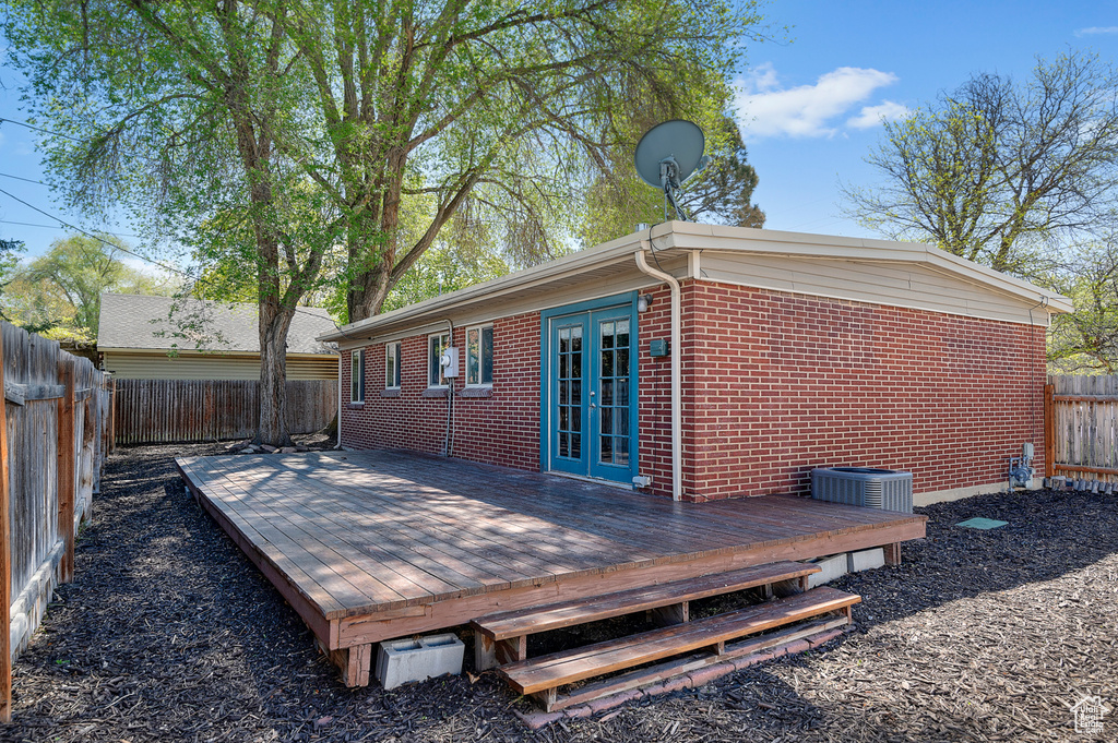 Wooden deck featuring central air condition unit, french doors, and a fenced backyard