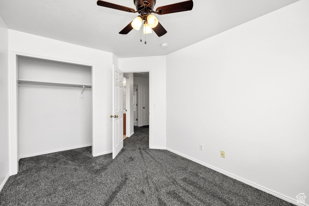 Unfurnished bedroom with dark carpet, baseboards, ceiling fan, and a closet