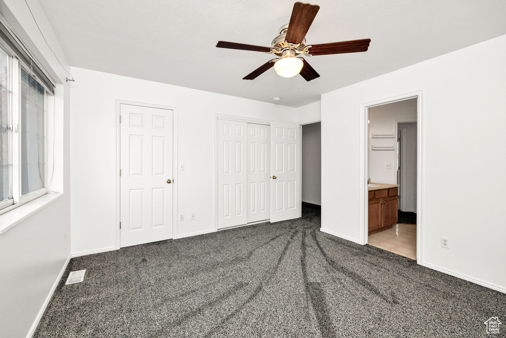 Unfurnished bedroom featuring ceiling fan, visible vents, baseboards, connected bathroom, and carpet