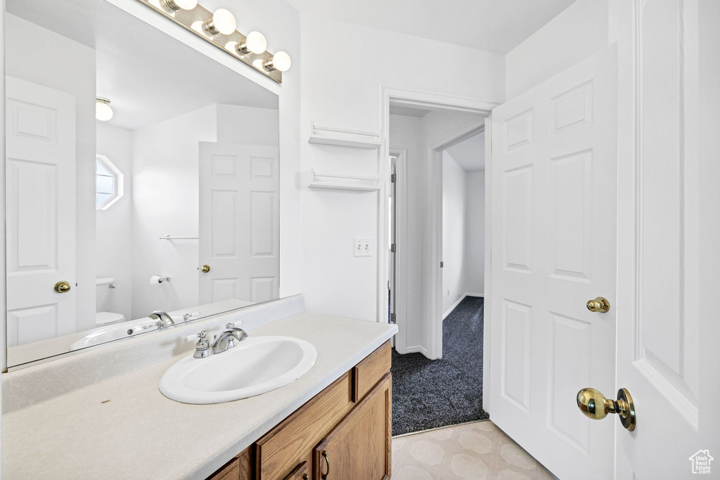 Half bathroom featuring vanity and toilet