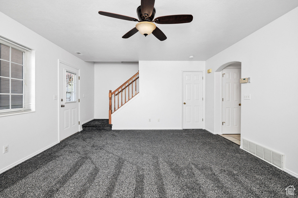 Interior space featuring stairs, a ceiling fan, visible vents, and carpet