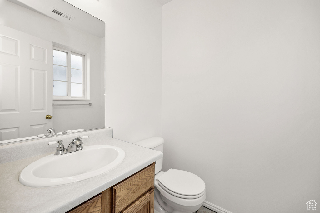 Half bathroom featuring vanity, toilet, and visible vents