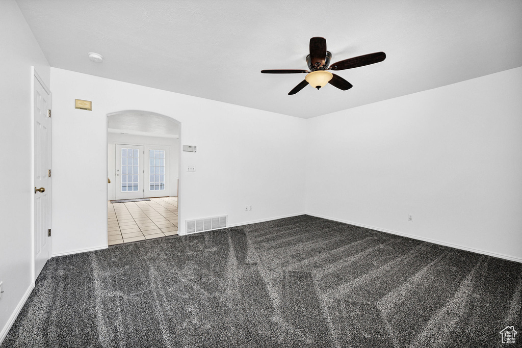 Carpeted spare room with arched walkways, ceiling fan, baseboards, and visible vents