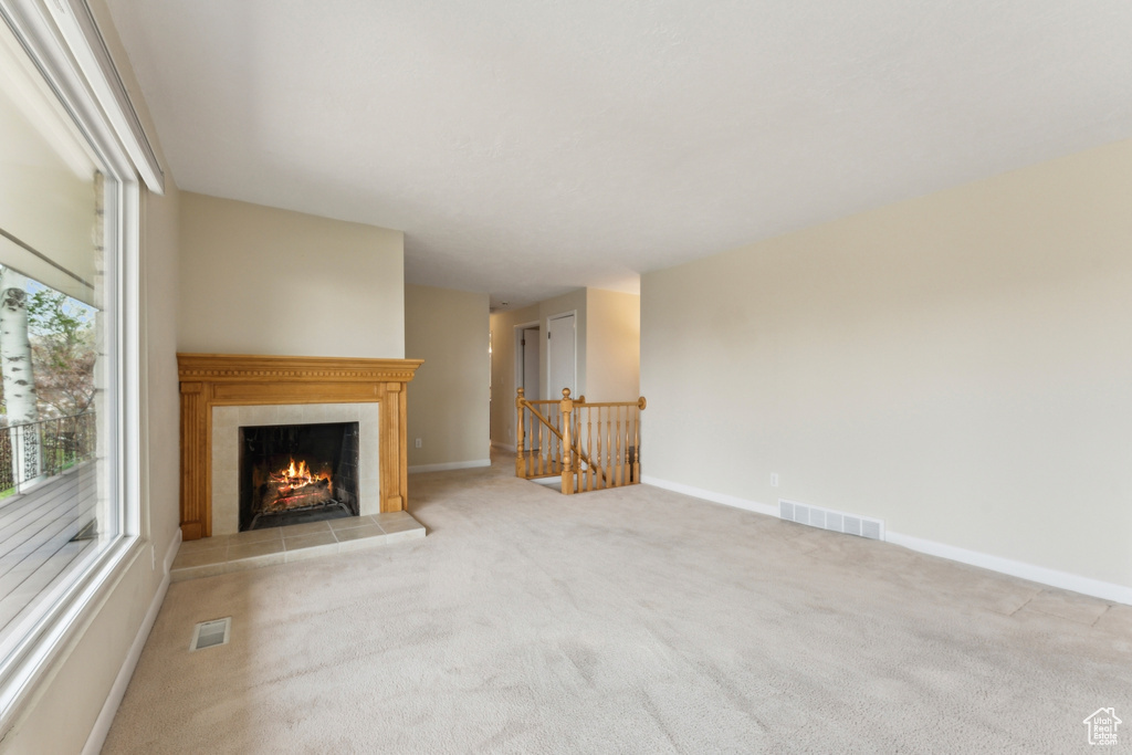 Unfurnished living room featuring baseboards, a fireplace, carpet flooring, and visible vents