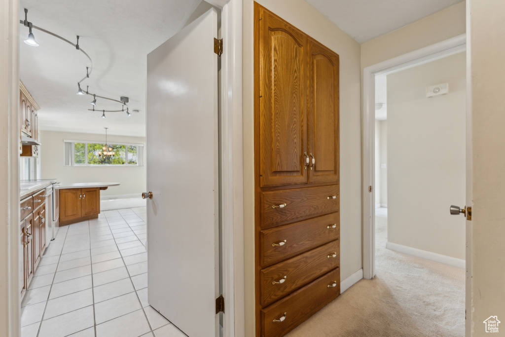 Corridor with baseboards, track lighting, and light tile patterned floors