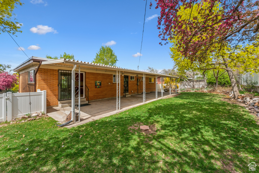 Rear view of property featuring a yard, brick siding, and a fenced backyard