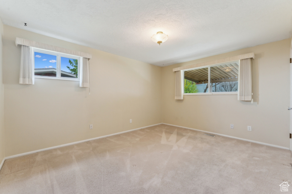 Empty room featuring carpet floors, baseboards, and visible vents