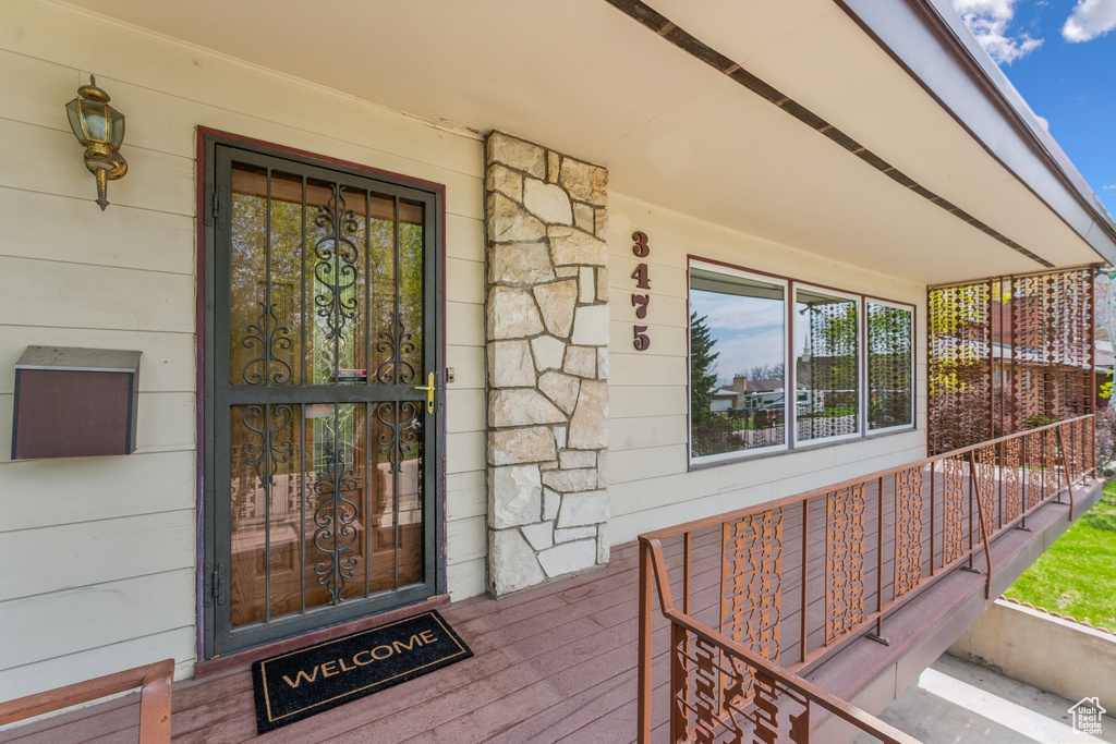 View of exterior entry featuring covered porch and stone siding