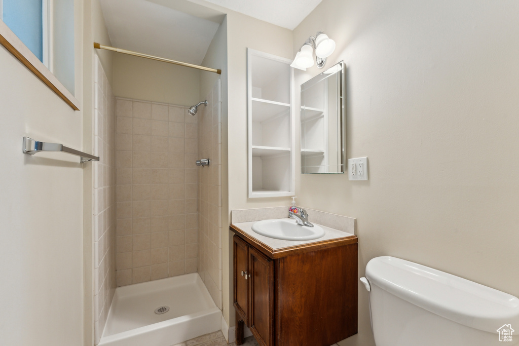 Full bath featuring vanity, toilet, and tiled shower