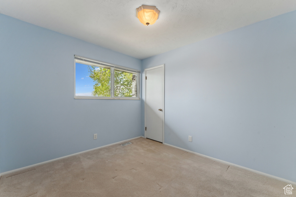 Spare room featuring baseboards, light colored carpet, and visible vents