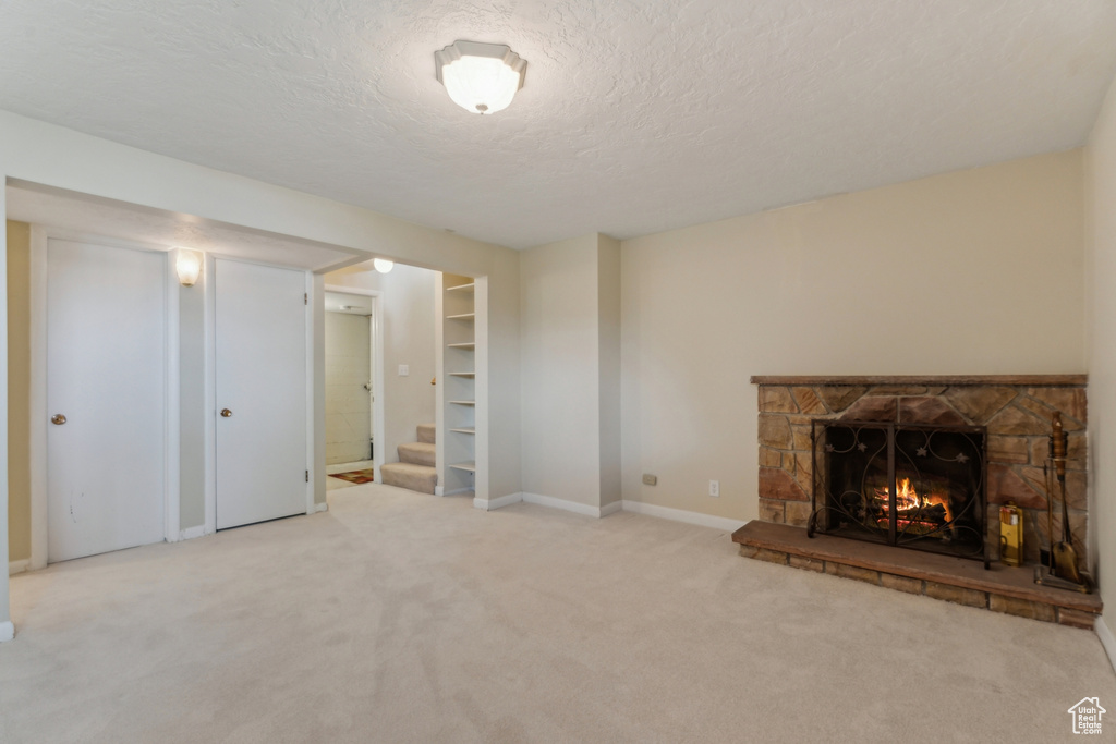 Unfurnished living room with a textured ceiling, a fireplace, stairway, carpet floors, and baseboards