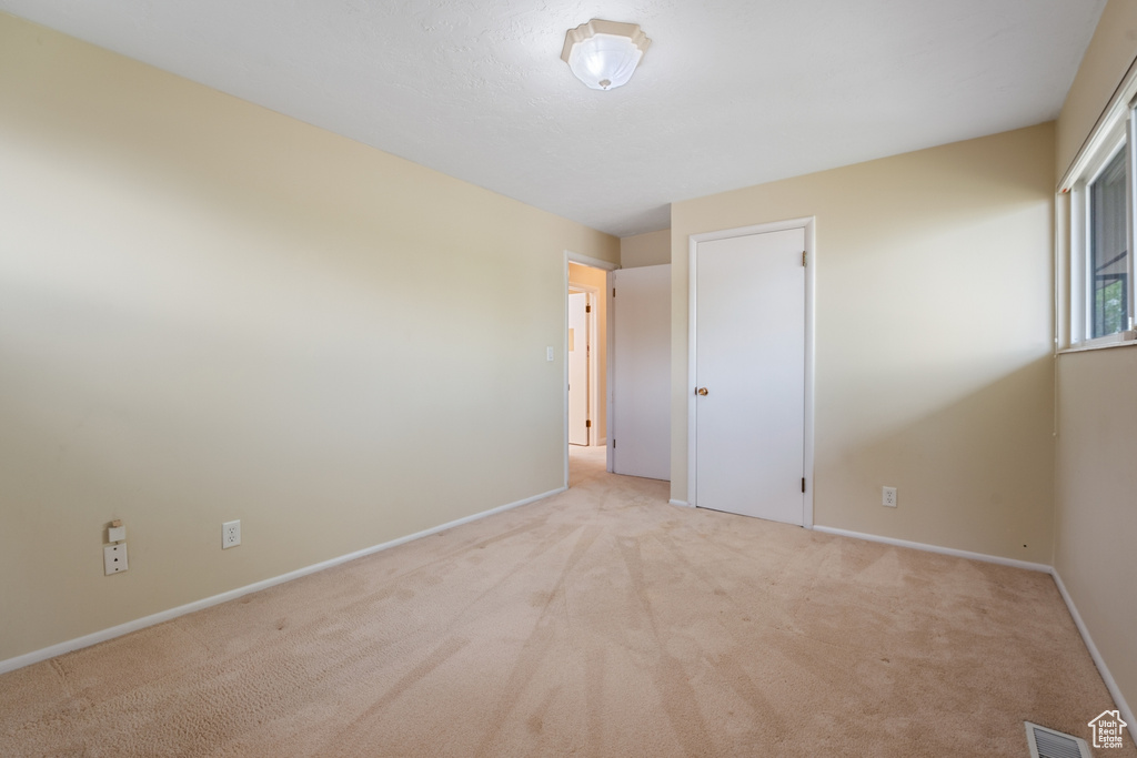 Unfurnished room featuring visible vents, baseboards, and light colored carpet