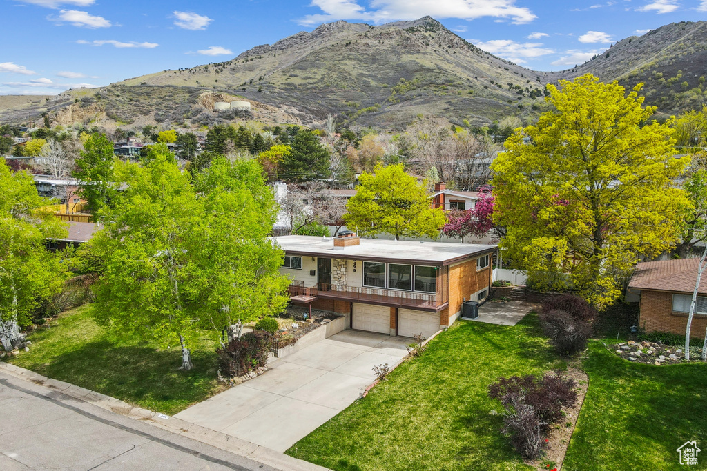 View of front of home with driveway, a mountain view, a front yard, and a garage