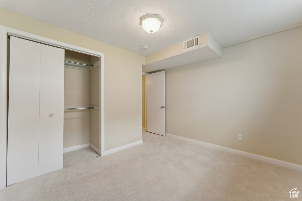 Unfurnished bedroom featuring a closet, carpet flooring, baseboards, and visible vents