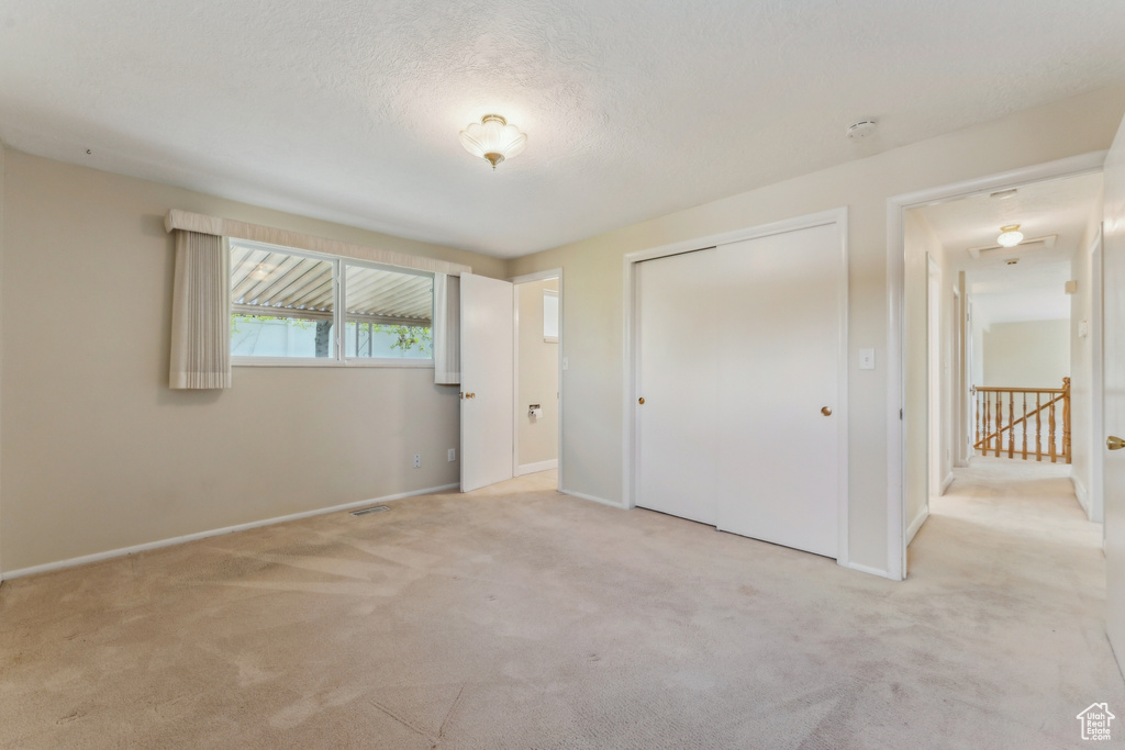 Unfurnished bedroom featuring baseboards, light carpet, a closet, and visible vents