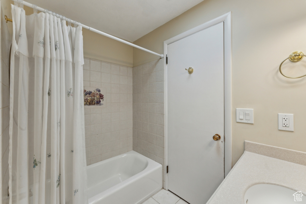 Bathroom featuring tile patterned floors, a sink, and shower / tub combo with curtain