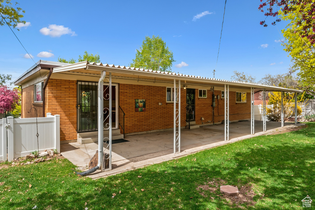 Rear view of house with a lawn, fence, brick siding, and entry steps