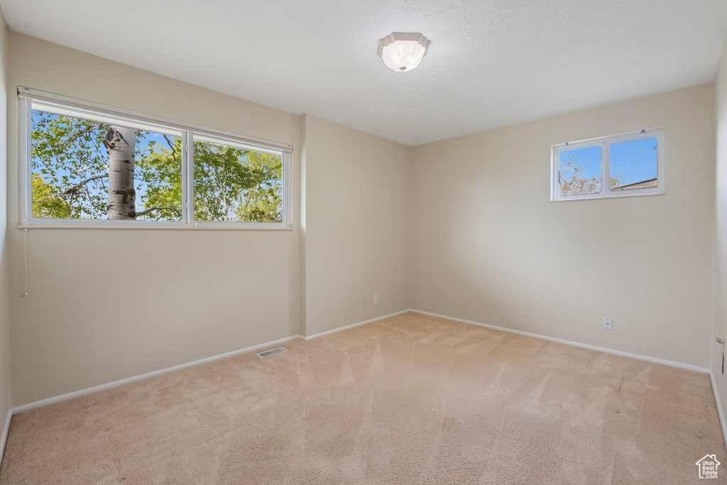 Carpeted empty room with baseboards and visible vents