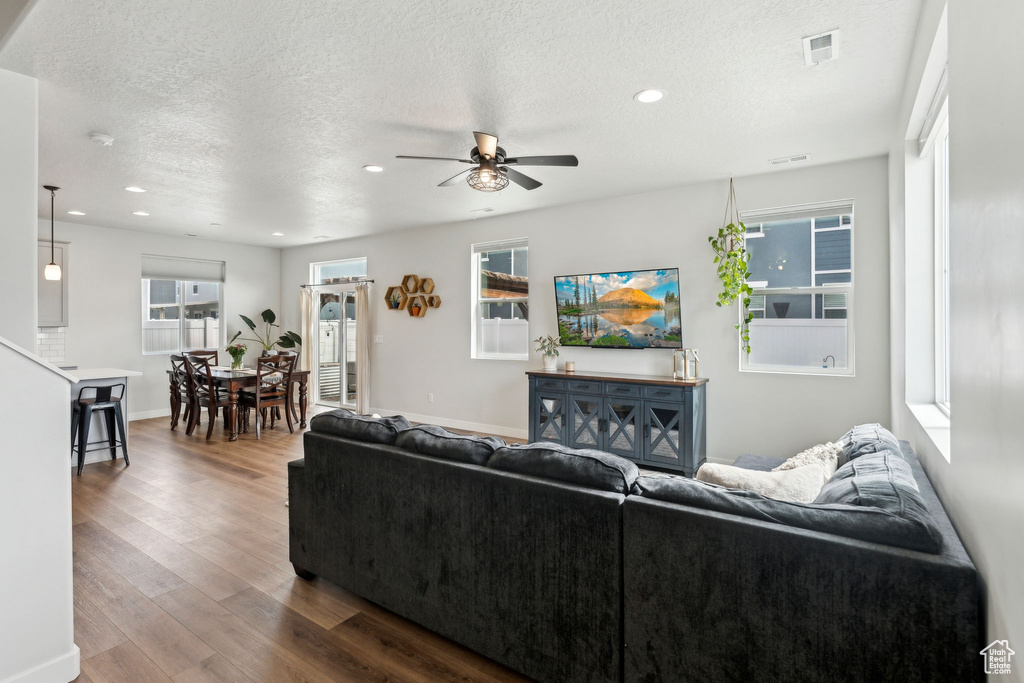 Living room with a ceiling fan, a textured ceiling, visible vents, dark wood finished floors, and recessed lighting