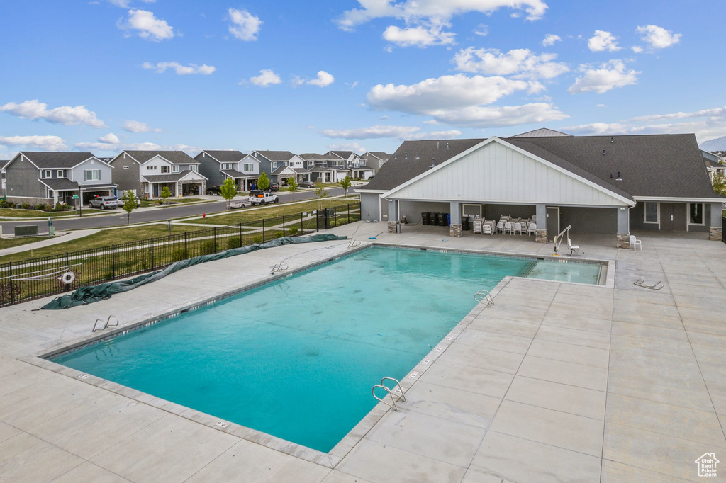 Community pool featuring a patio, fence, and a residential view