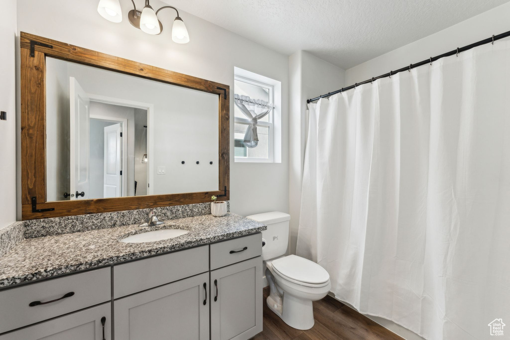 Full bath featuring toilet, a textured ceiling, wood finished floors, and vanity