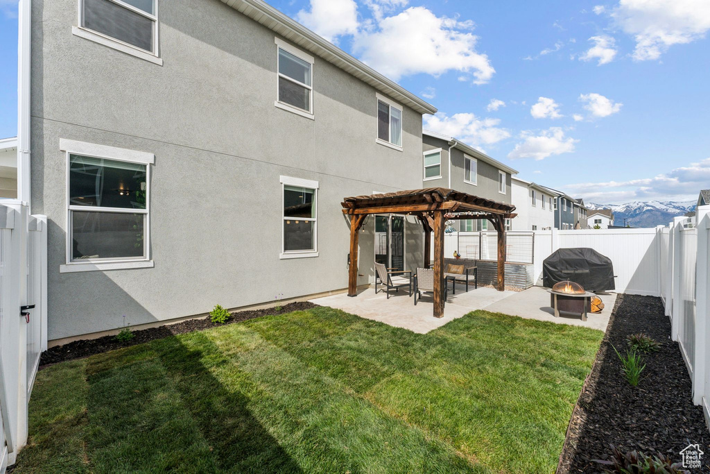 Rear view of house with a patio area, a fenced backyard, a yard, a pergola, and a fire pit