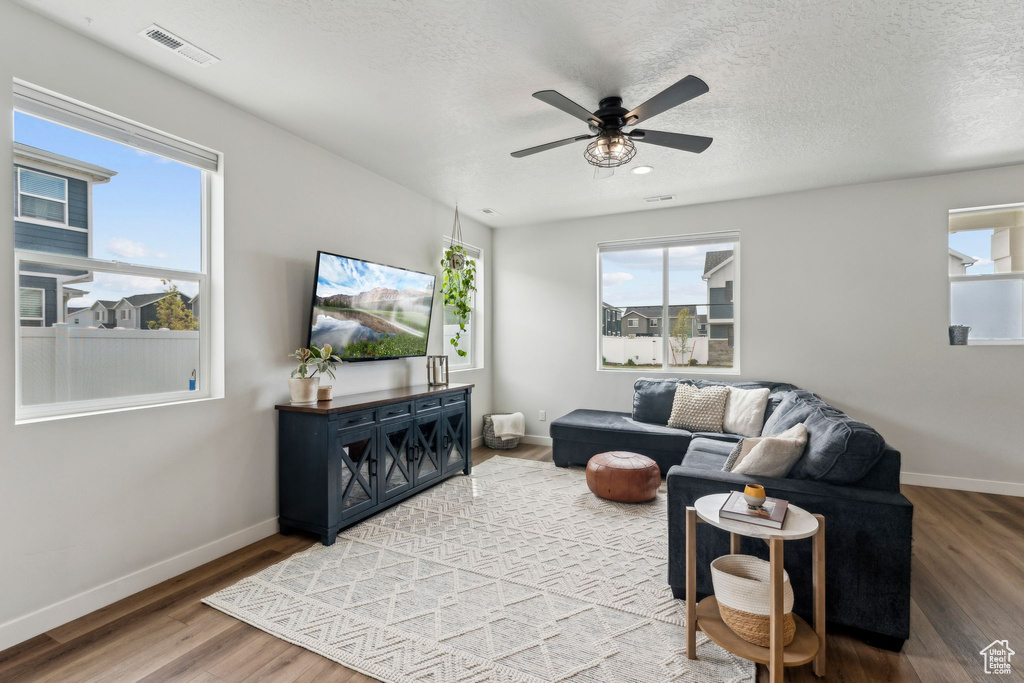 Living room with baseboards, visible vents, plenty of natural light, and wood finished floors