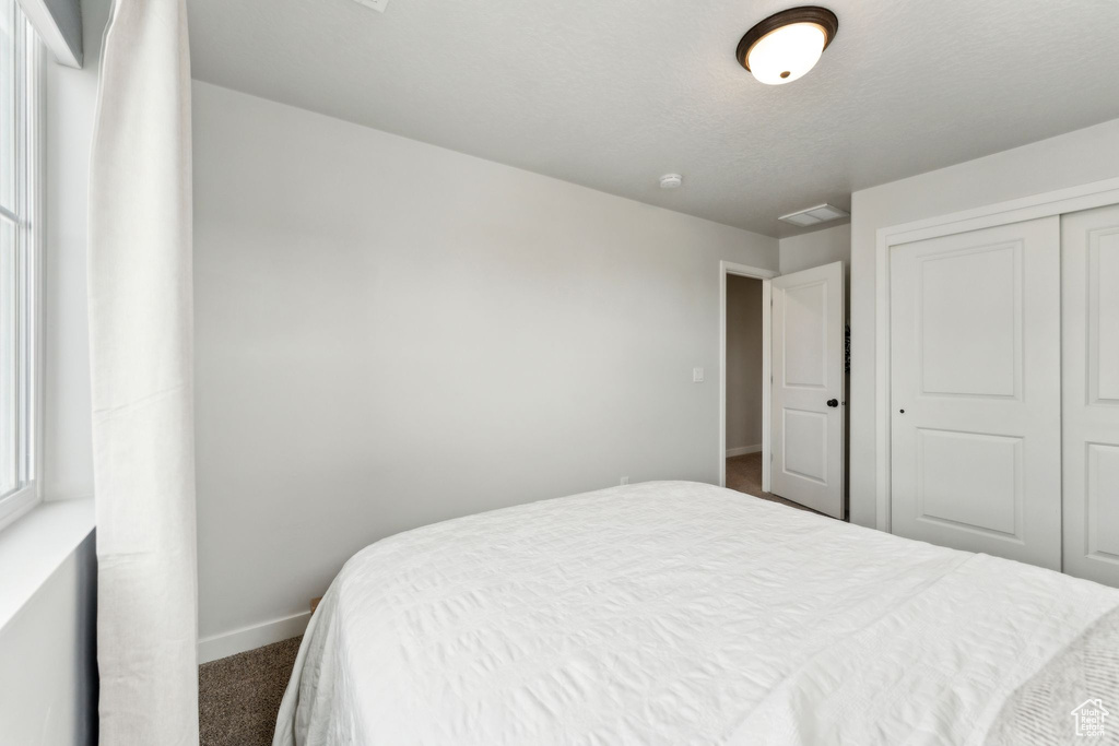 Bedroom featuring a closet, baseboards, and dark colored carpet
