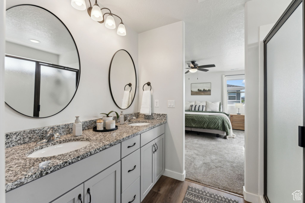 Bathroom with connected bathroom, ceiling fan, a sink, a textured ceiling, and wood finished floors